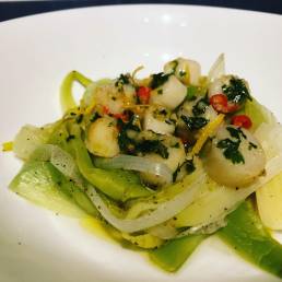 Fresh scallops with lemon and chilli butter served on a nest of leeks
