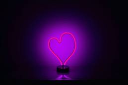 Neon light in heart shape and purple in colour